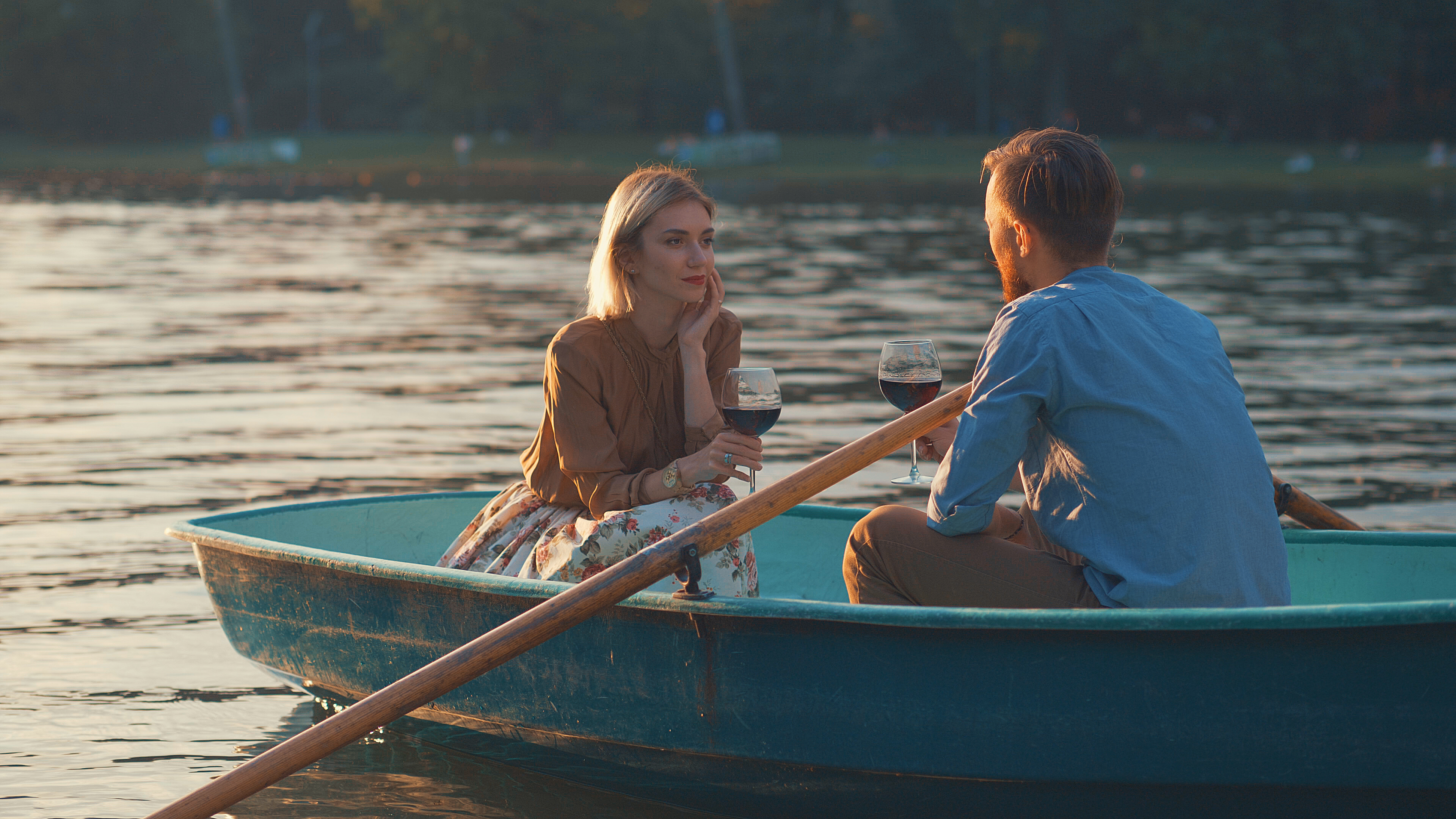 Couple on a rowing boat at sunset on a date. He set it up after reading Summer Date Ideas In The UK - Are you familiar with modern dating trends?